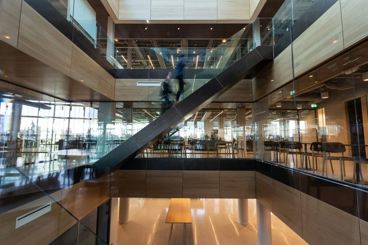 Man in black jacket walking on brown wooden floor